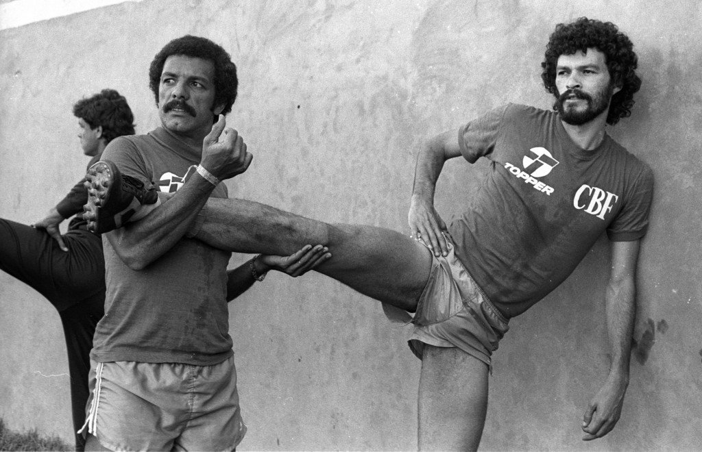 BRAZILIAN SOCCER TEAM'S JUNIOR HELPS TEAM MATES SOCRATES DO A LEG STRETCH DURING PHYSICAL TRAINING ...